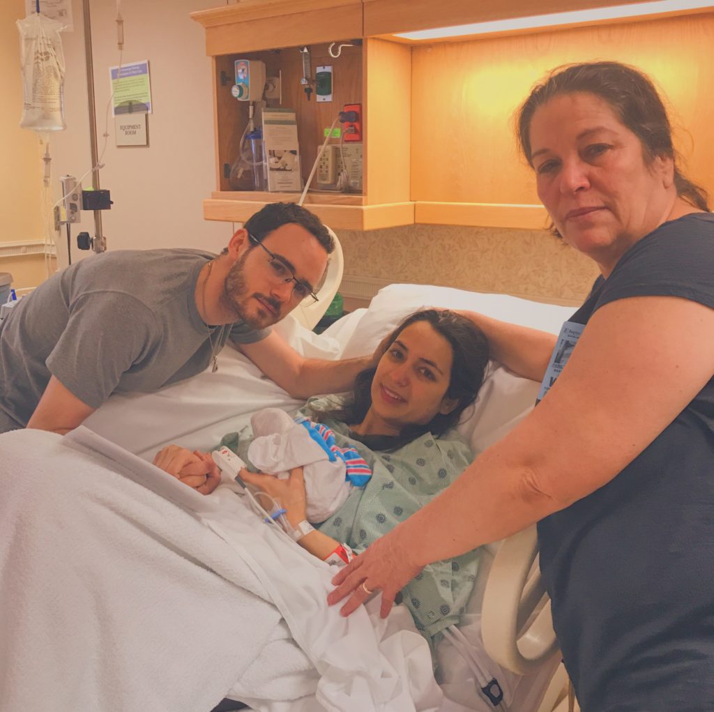 Picture showing Estefi holding Noah wrapped in blankets, with Jon and her mom on either side.