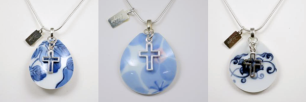 A picture of three necklaces from Nozomi Project's Kumiko series. Rounded shards of blue patterned china with a silver cross hanging over and a small pendant reading 'hope' attached a the top.